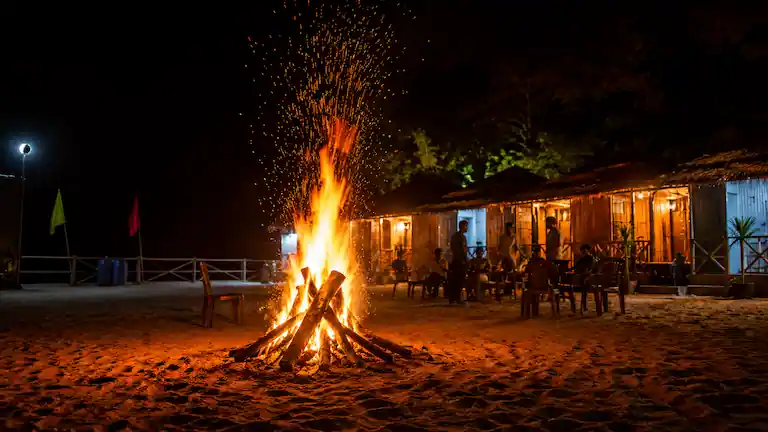 Bonfire on the sand at a Mousuni Island beach camp at night.