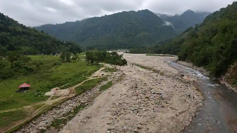 A scenic view of the Bunkulung farming village with a river and green hills.