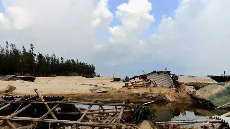 Makeshift structures and wooden fishing boats resting on the sand at the Dadanpatrabar Khoti.