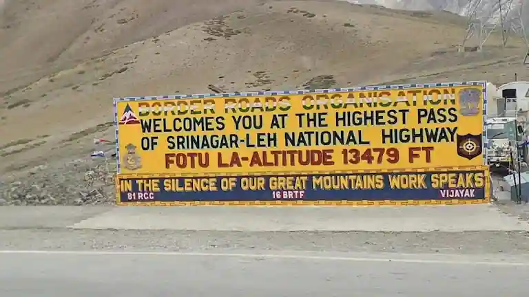 Yellow altitude signboard at Fotu La Pass on the Leh to Kargil Bus Service route.