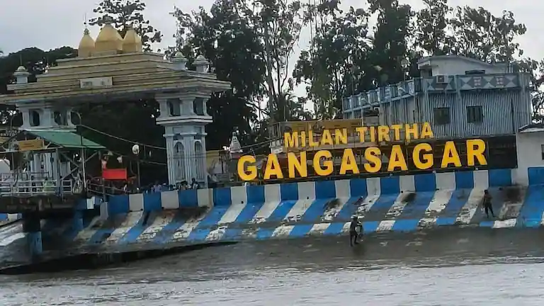 The Milan Tirtha Gangasagar sign at the ferry ghat showing the mud banks during low tide.