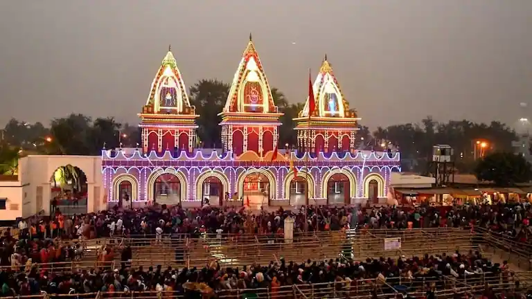Crowded Kapil Muni Temple with festival lights and queue barricades during Gangasagar Mela.