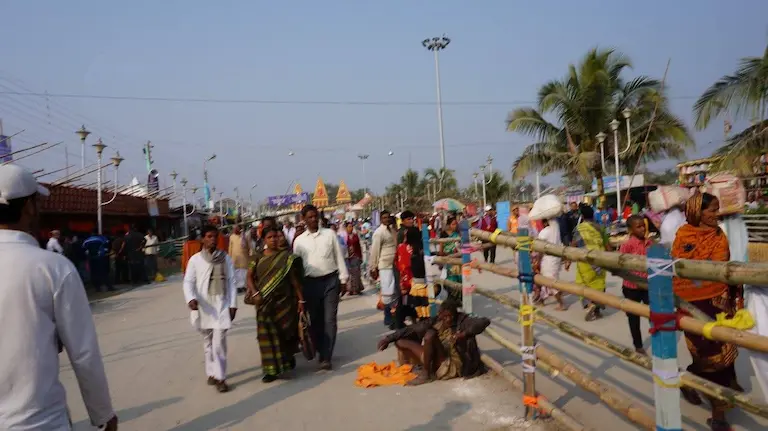 Pilgrims walking past bamboo barricades towards the temple, showing why choosing the best time to visit Gangasagar matters.