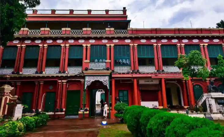 Red exterior of Jorasanko Thakur Bari with green windows.