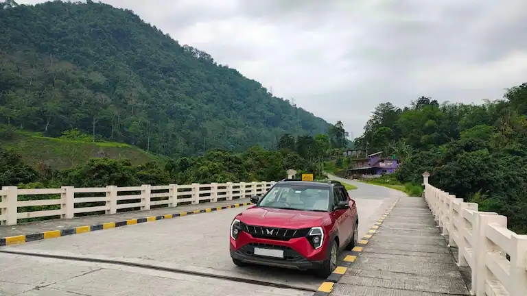 Red car parked on a mountain bridge during the Kolkata to Sikkim drive.