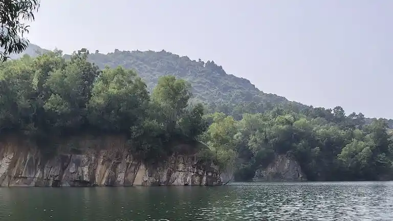 A serene lake surrounded by the green rocky cliffs of the Nilgiri Hills near Panchalingeswar, Balasore.