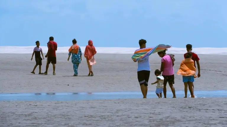 Tourists walking across the wide, flat sand during low tide at Bakkhali Sea Beach, one of the top places to visit in Bakkhali.