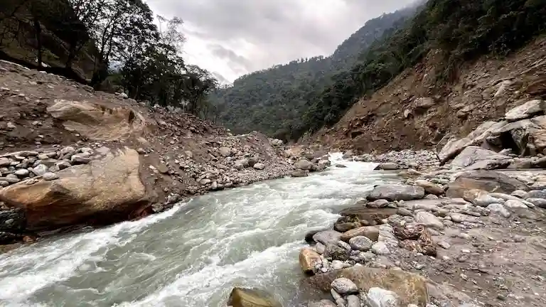 Fast-flowing river surrounded by eroded mountain terrain on the Gangtok to Darjeeling route.
