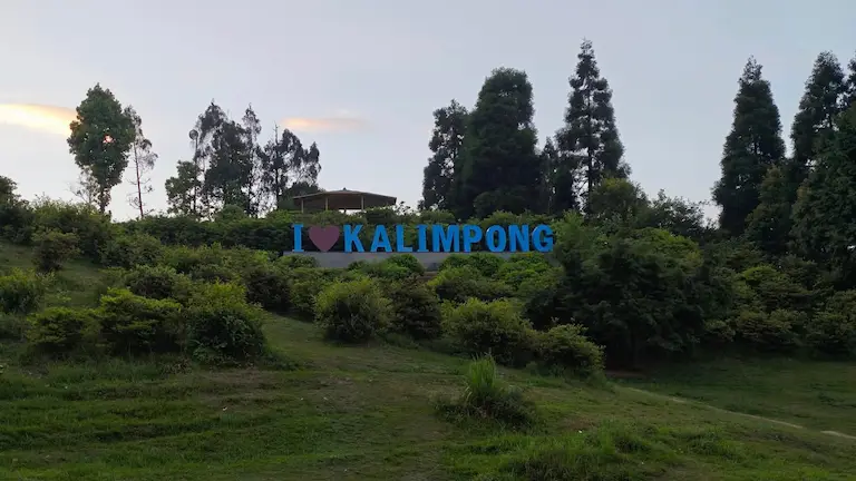 The I Love Kalimpong signboard surrounded by green bushes and trees at Delo Park.