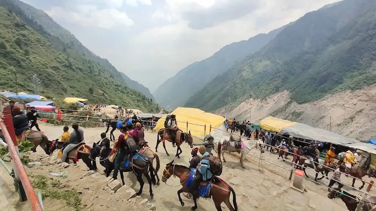 Trekkers and mules navigating a narrow, crowded stone path on the steep mountain route.