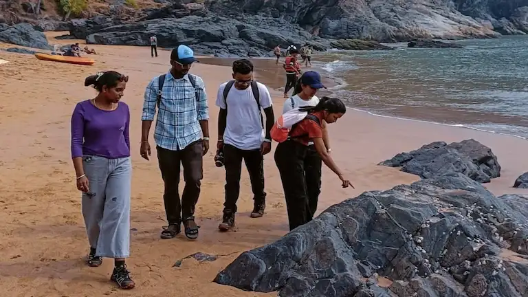 Hikers walking on the sand and rocks at Kudle Beach.