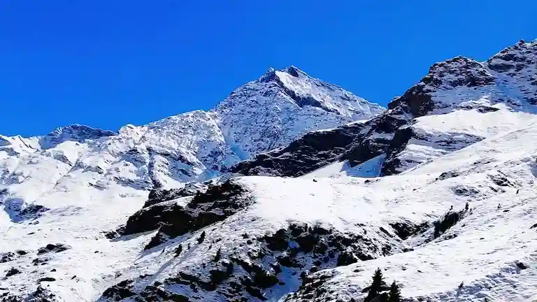 Heavy snow on the high mountain peaks of Lahaul Valley against a bright blue sky