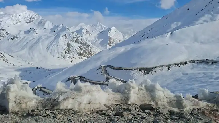 Snow-covered winding dirt road at Shinkula Pass on the Manali to Zanskar route