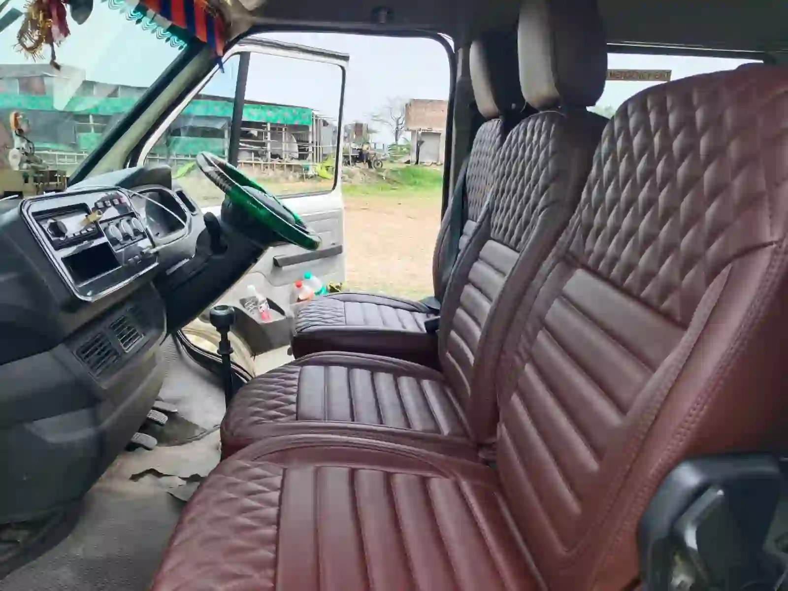 Front driver cabin and passenger bench seats in a Kolkata Tempo Traveller.
