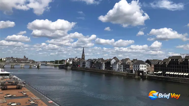 A sunny view of the River Maas, the historic waterfront architecture, and the Sint Servaasbrug, highlighting the best things to do in Maastricht.