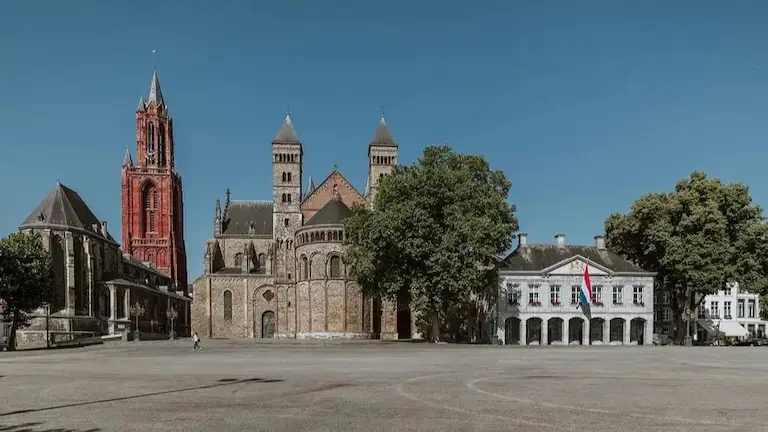 A wide view of the historic Vrijthof square showing the red Sint Janskerk tower and Saint Servatius Basilica.