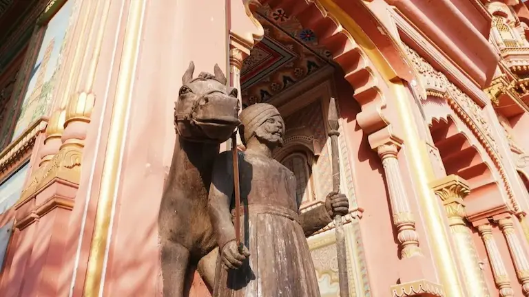 Close-up of a stone guard and horse statue carved into the pink pillars of Patrika Gate, Jaipur.