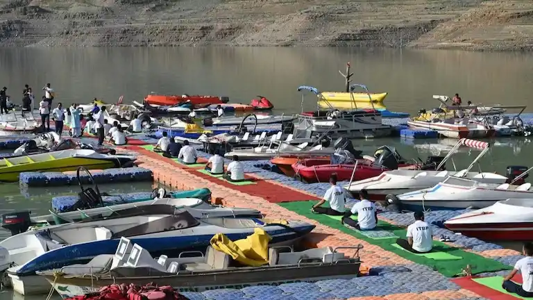 Speedboats docked at the colorful floating pontoons in Tehri Lake with exposed dry banks.