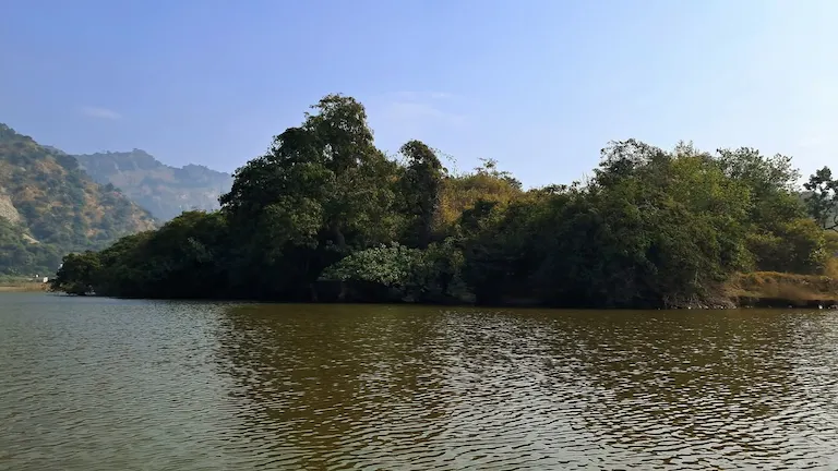 View of the green shoreline and Shivalik hills from a boat on Tikkar Taal.